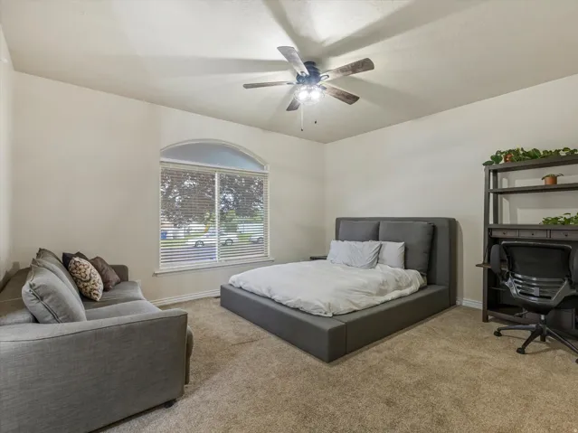 Bedroom #2 featuring a vaulted ceiling with a ceiling fan, arched window with blinds, and neutral carpet flooring