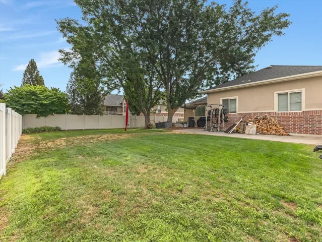 Expansive grassy yard area with a white vinyl privacy fence