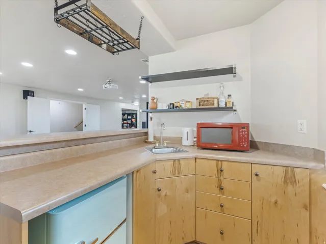Wet bar featuring a stainless steel sink, wood-finish cabinetry, and laminate countertops