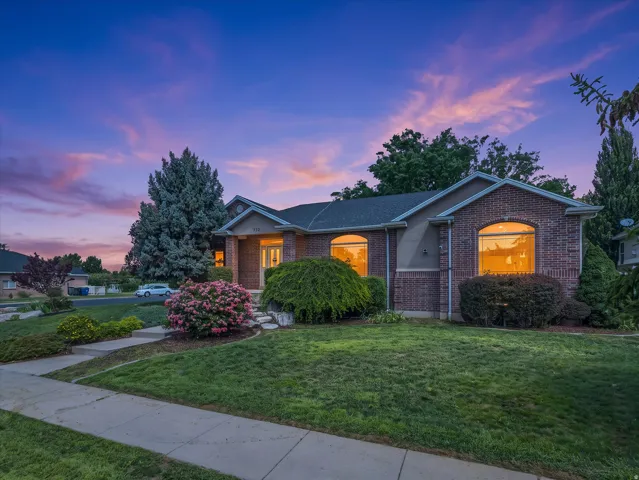 Brick exterior with stucco accents, arched windows, covered entry, and mature landscaping
