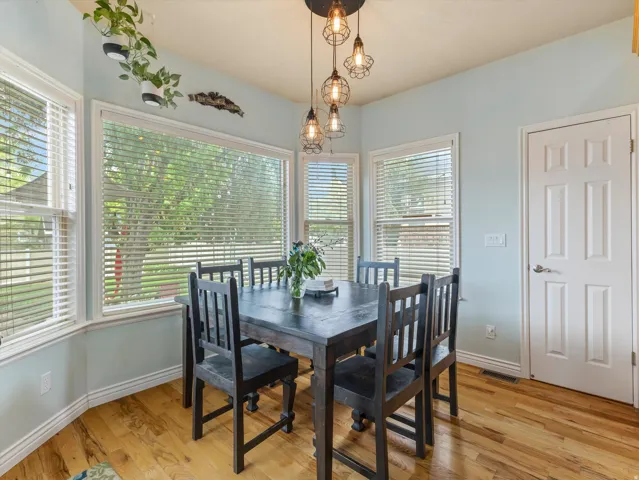 Bay window with multiple panels, wood-finish flooring, and a modern chandelier