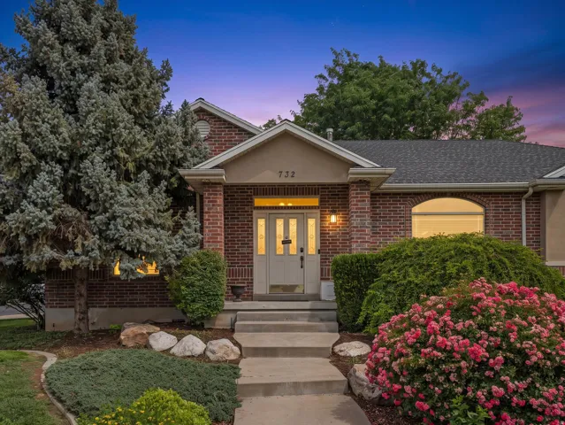 Brick facade residence with a prominent entryway, arched window, and mature landscaping