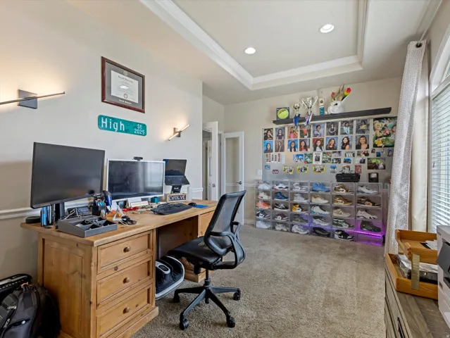 Versatile room featuring a tray ceiling with recessed lighting, wall sconces, wood-finish flooring, and a large arched window with horizontal blinds
