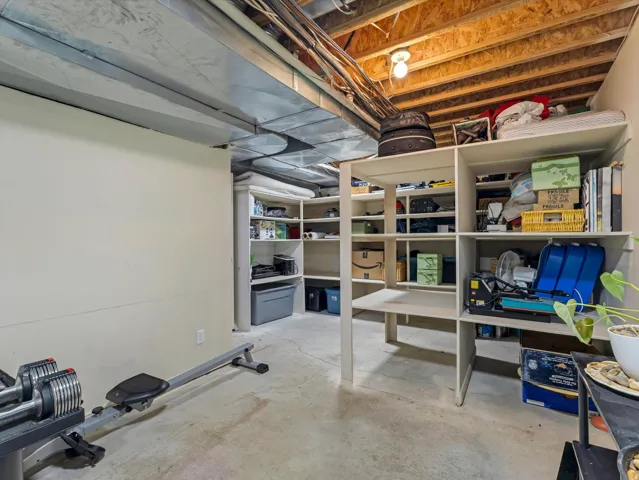 Unfinished basement space featuring exposed ceiling joists and concrete flooring