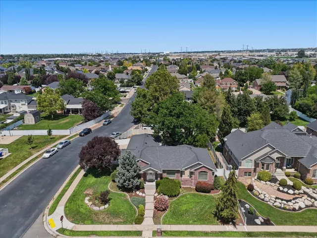 Brick exterior residence with a dark shingle roof, established landscaping, and a curvilinear paved walkway