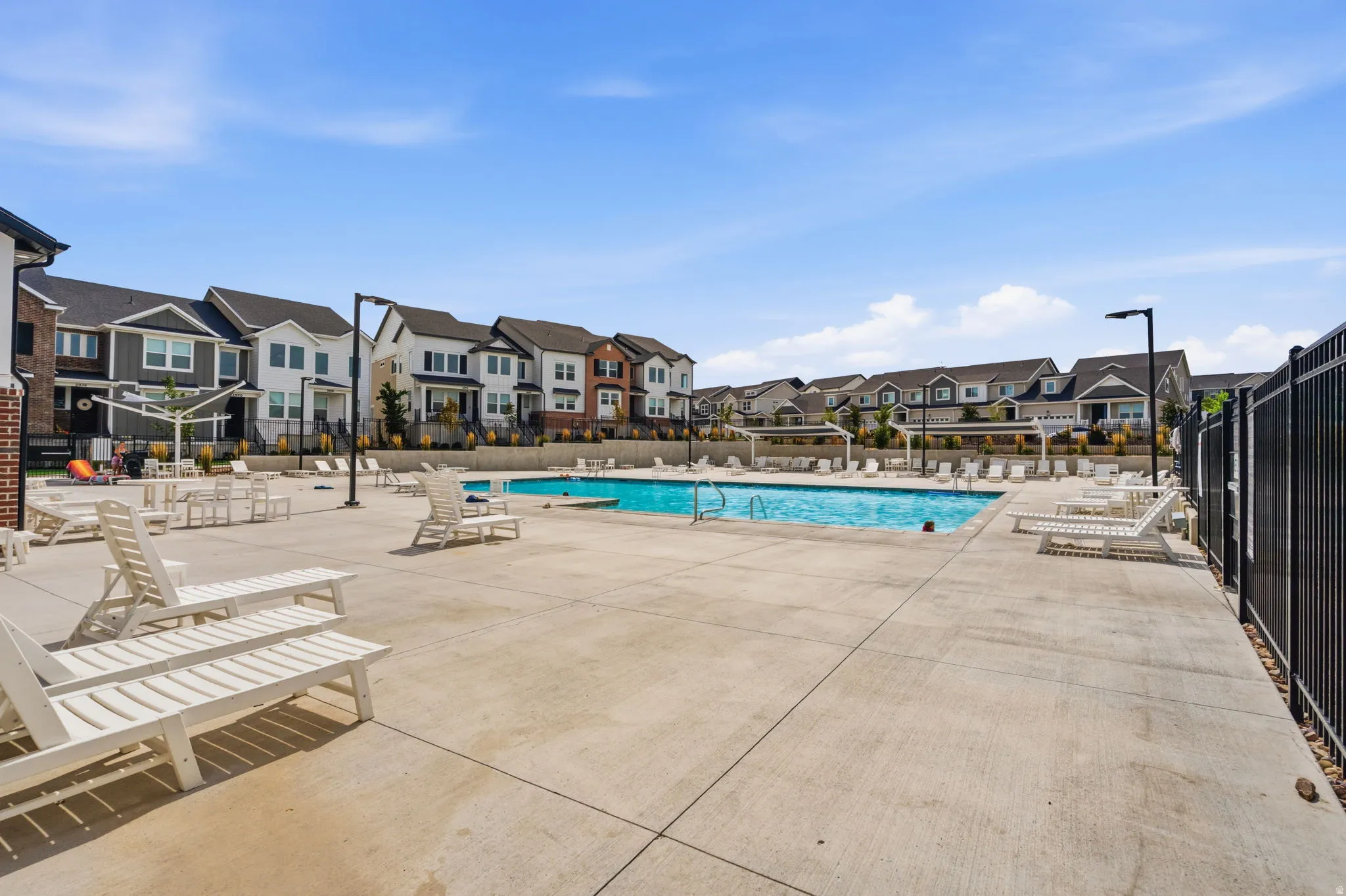 Community swimming pool surrounded by concrete decking and metal fencing