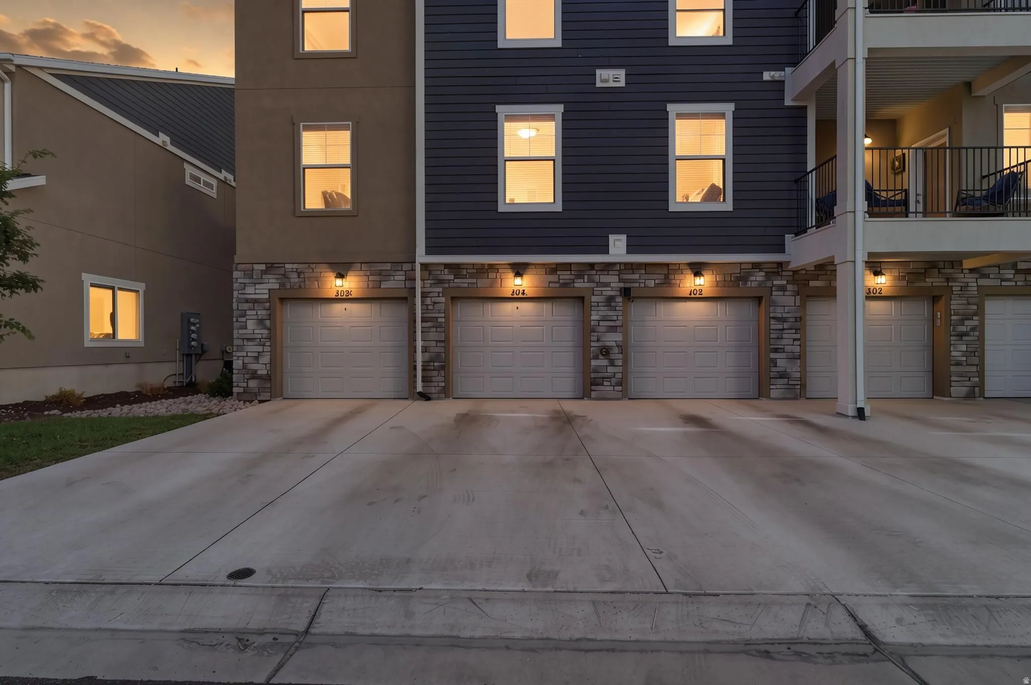 Multi-level residential facade featuring individual garage doors with integrated lighting fixtures