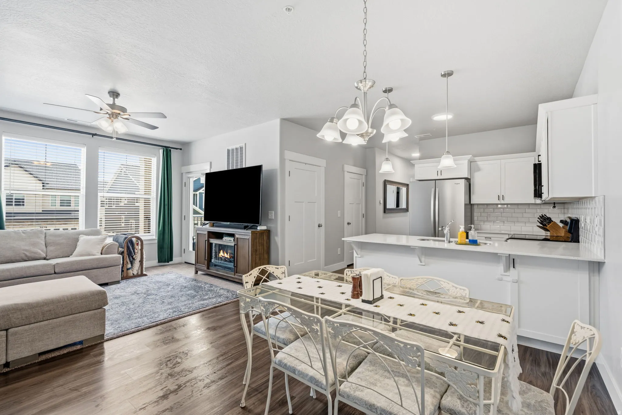 Open-concept living space with wood-finish flooring, a contemporary ceiling fan, and multiple windows