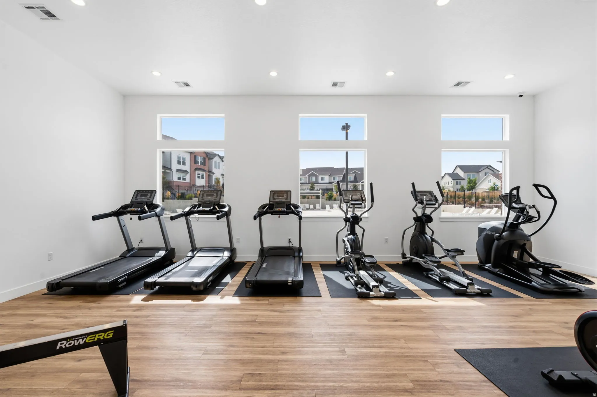 Dedicated fitness room featuring wood-finish flooring, recessed lighting, and multiple windows