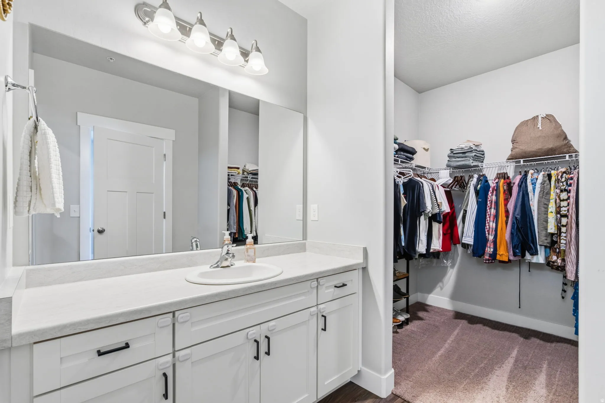 Vanity featuring an integrated sink, broad mirror, and modern light fixture