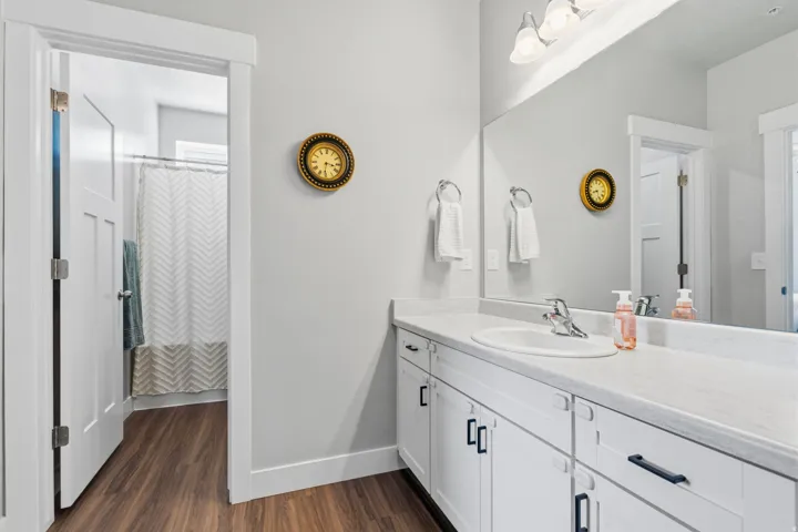 Bathroom vanity featuring a single basin sink, light-toned countertop, and white cabinetry with dark hardware