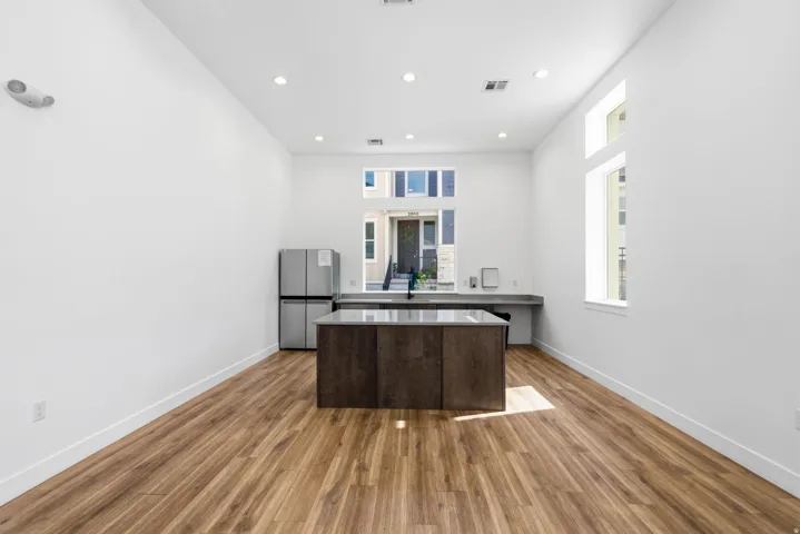 Spacious open-concept area featuring wood-finish flooring, recessed lighting, and large windows