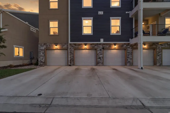 Multi-level residential facade featuring individual garage doors with integrated lighting fixtures