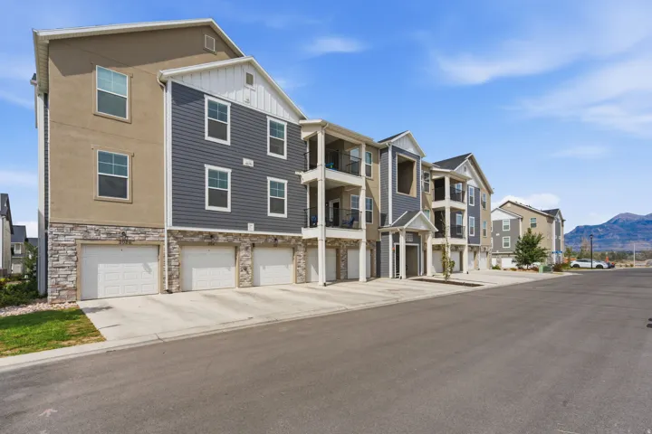 Modern multi-story residential building featuring a stone veneer base, stucco, and horizontal siding