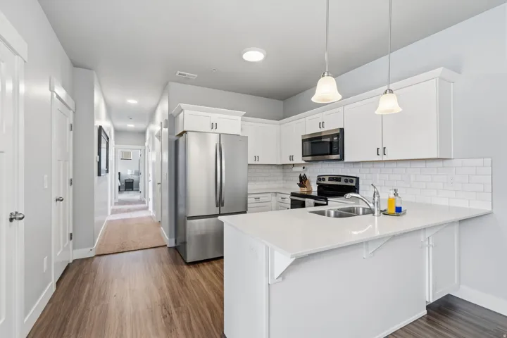 Kitchen featuring white cabinetry, stainless steel appliances, white subway tile backsplash, and light-toned countertops