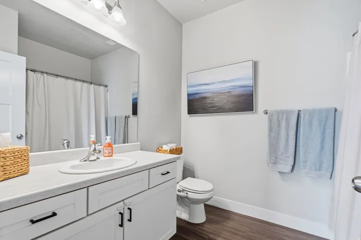 Bathroom featuring a single vanity with a white countertop, undermount sink, and white cabinetry with black hardware