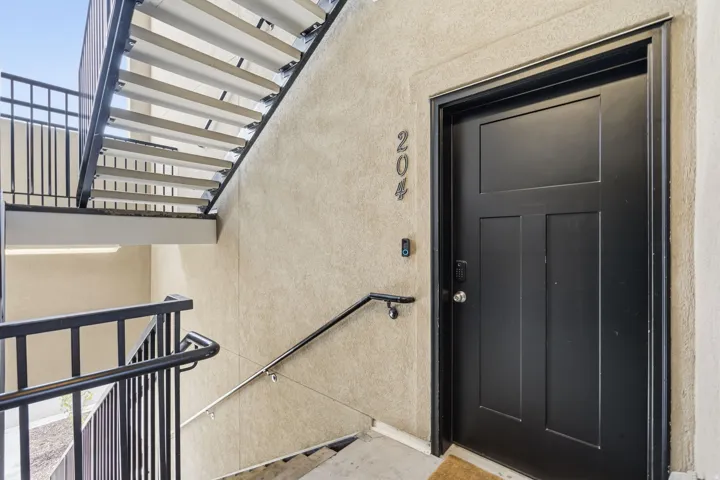 Black paneled entry door with modern numeric address and integrated smart lock system