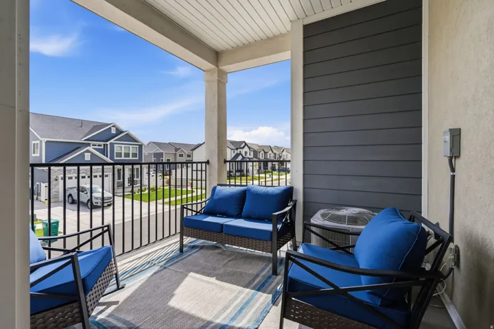 Covered balcony featuring a white railing and a textured wall