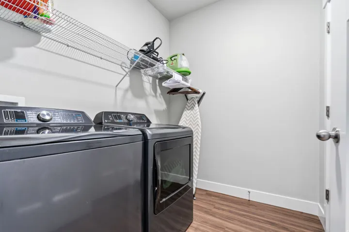 Dedicated laundry area featuring wood-finish flooring, white walls, and a white door with a brushed nickel knob