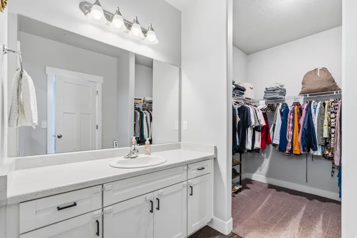 Vanity featuring an integrated sink, broad mirror, and modern light fixture