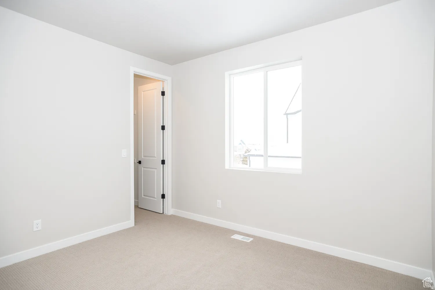 Carpeted room with a double-pane window, white trim, and a panel door with dark hardware