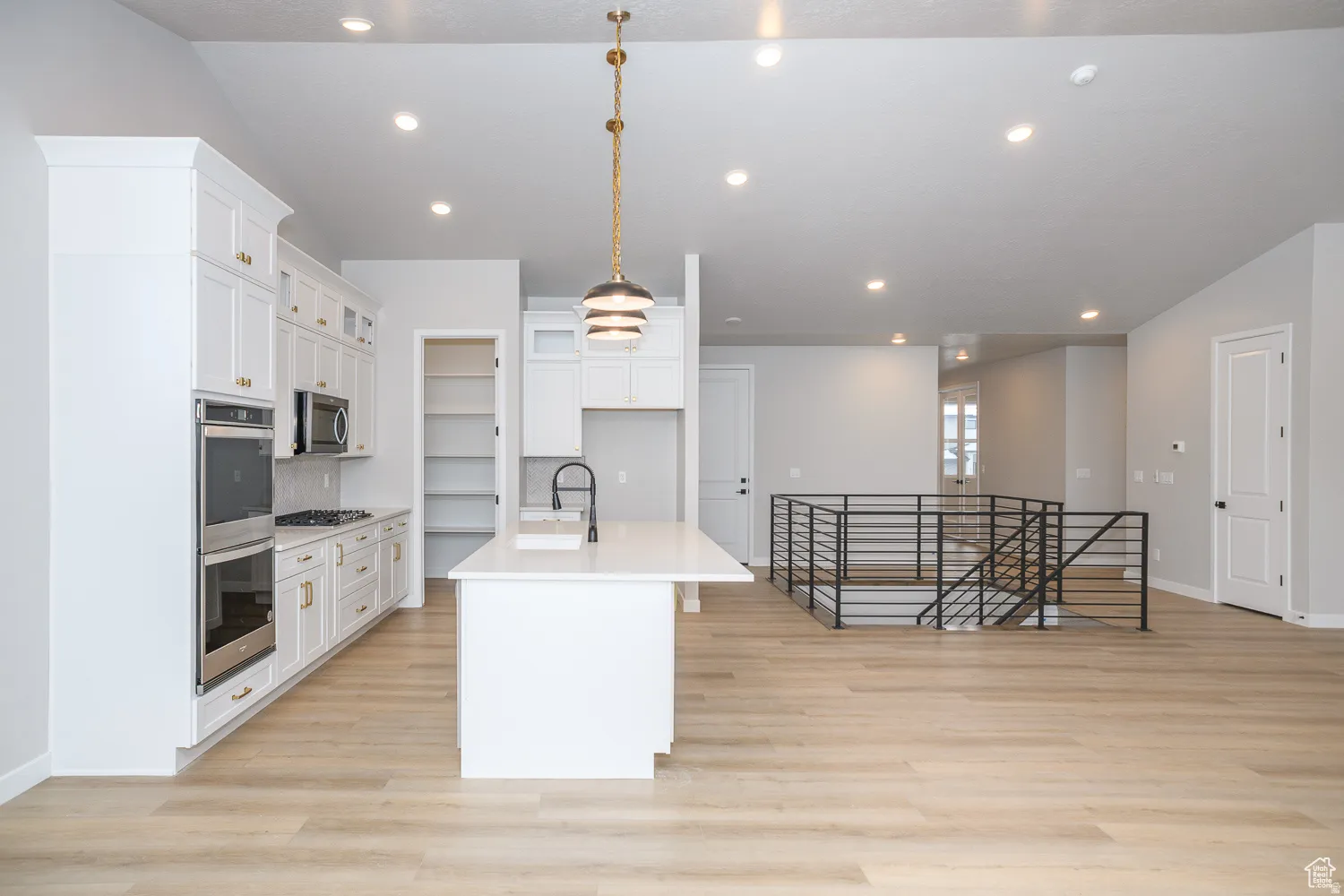 Kitchen area featuring a central island with a sink and a contemporary pendant light fixture