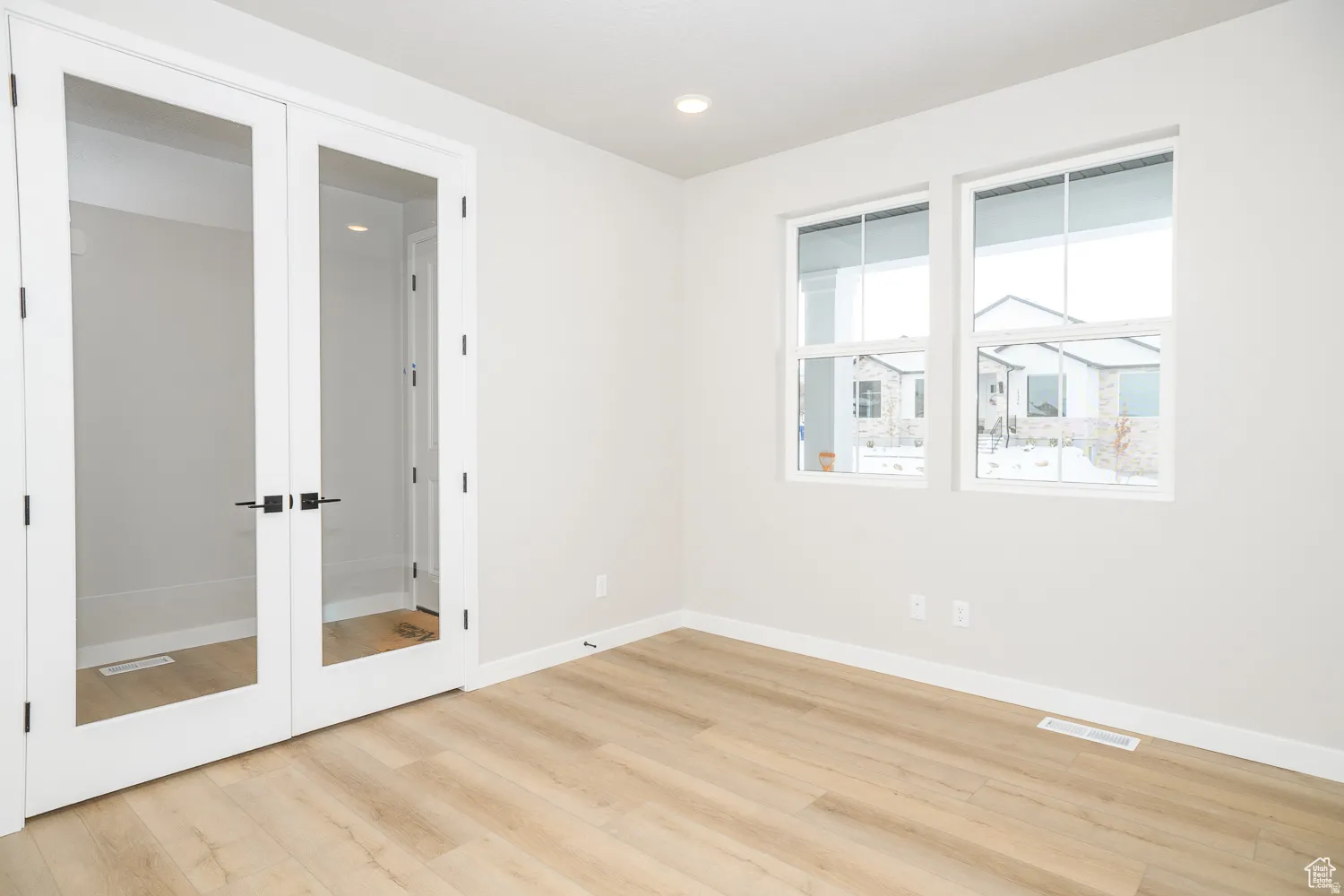 Bright interior space featuring wood-finish flooring, white baseboards, and light gray walls
