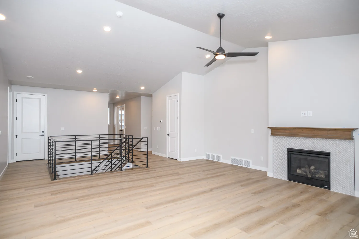 Spacious living area featuring vaulted ceilings with recessed lighting, wood-finish flooring, and a contemporary ceiling fan