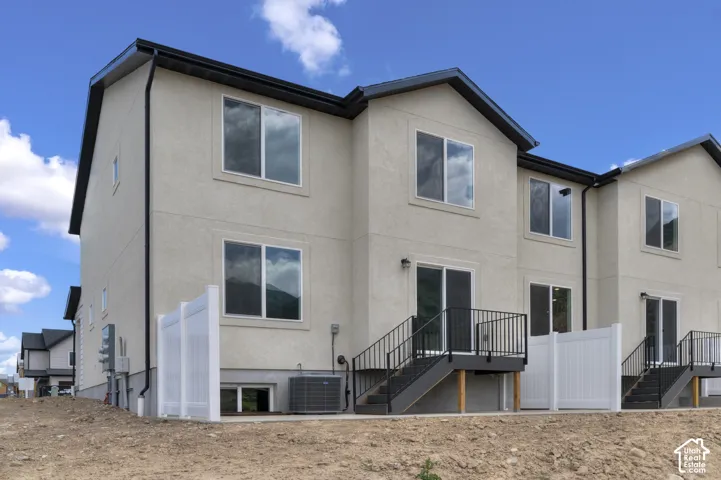 Multi-story stucco exterior featuring multiple windows and a black roof