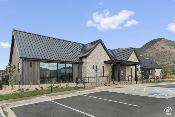 Modern architectural design featuring a prominent metal roof, stone facade, and wood-finish siding