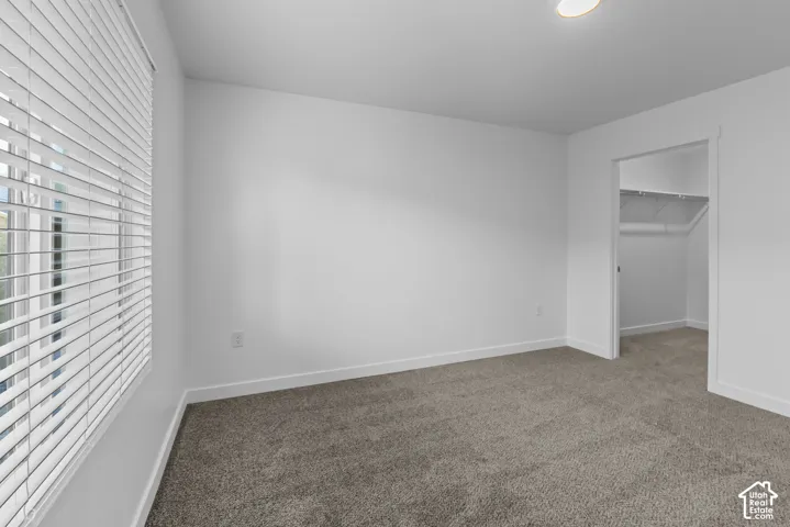 Carpeted room featuring a window with blinds, white walls, and a recessed ceiling light