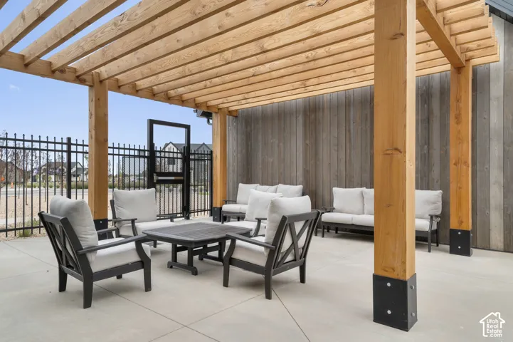 Spacious patio featuring a wood pergola, concrete flooring, and a vertical wood plank wall