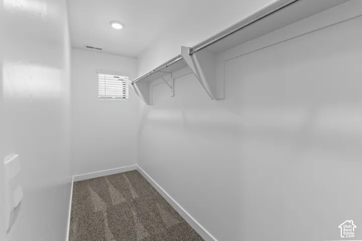 Walk-in closet featuring built-in shelving, a clothes rod, recessed lighting, and a window with blinds