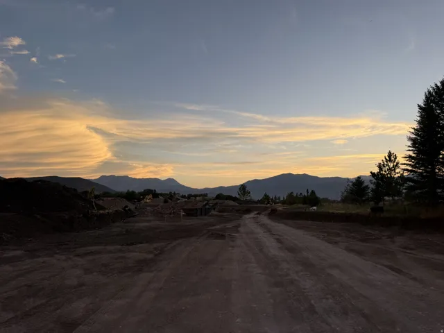 Expansive terrain with a visible dirt road, framed by distant mountains and a serene sky