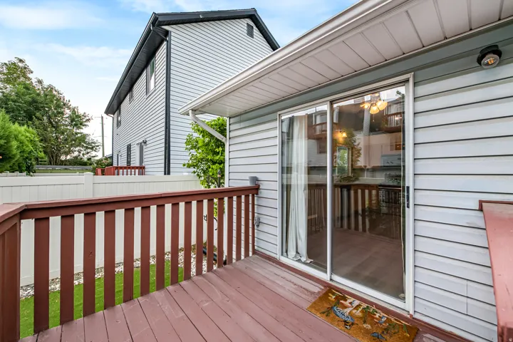 Wood-finish deck with a brown railing, white siding exterior, and sliding glass door