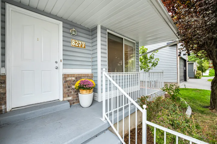 Inviting front porch featuring a white entry door, light blue siding, and a stone veneer accent