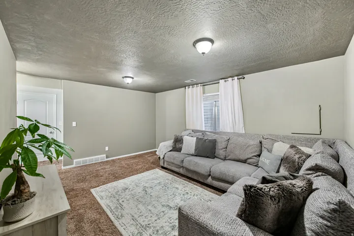 Carpeted interior space featuring light gray wall paint and a textured ceiling