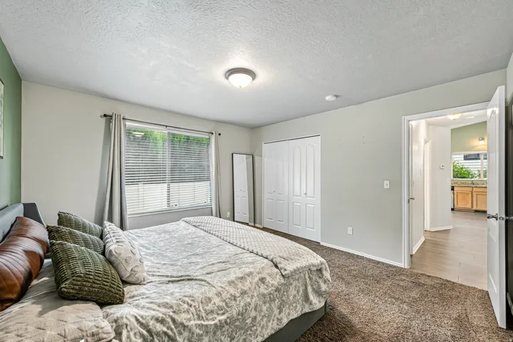 Bedroom featuring light gray walls, a window with horizontal blinds, and a built-in double-door closet
