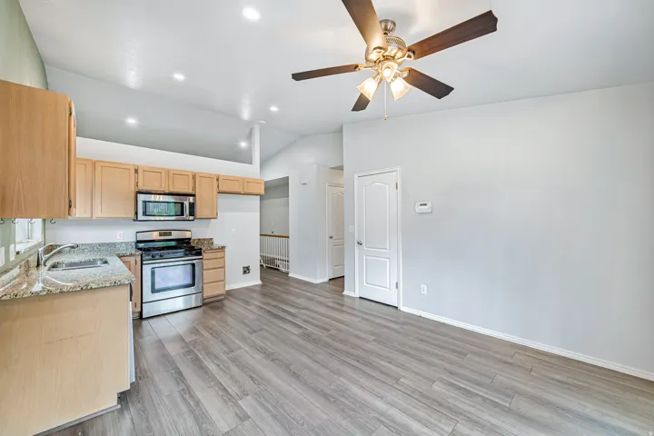 Open concept kitchen and living area featuring wood-finish flooring, vaulted ceilings, and recessed lighting