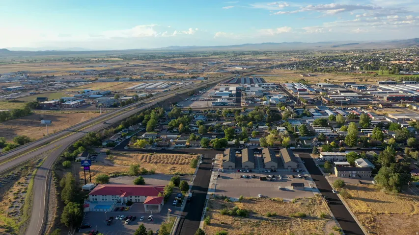 Expansive aerial overview of a mixed-use commercial and residential area, featuring a multi-lane highway, commercial structures, and residential streets