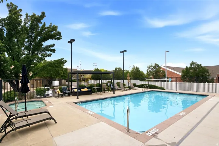 Outdoor pool area featuring a rectangular swimming pool, an integrated spa, and concrete decking
