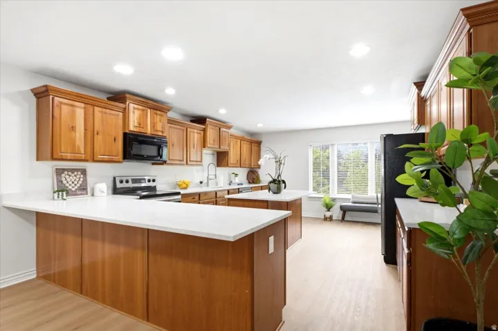 Spacious kitchen featuring warm wood cabinetry, white countertops, built-in microwave, and recessed lighting