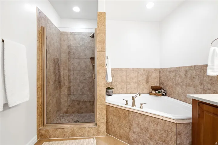 Corner soaking tub with brushed nickel fixtures, a tiled surround, and integrated shelving