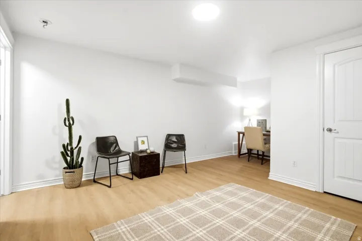 Spacious interior room featuring light wood-finish flooring, white baseboards, and bright white walls