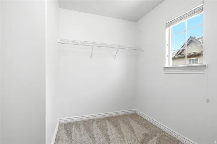 Carpeted room with a single window featuring horizontal blinds and a window sill