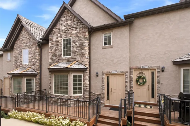 Stone and stucco exterior featuring multiple gables and bay windows