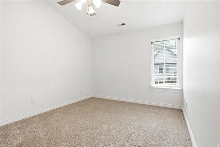 Neutral-toned carpet flooring complementing bright white walls, accented by a single window with blinds