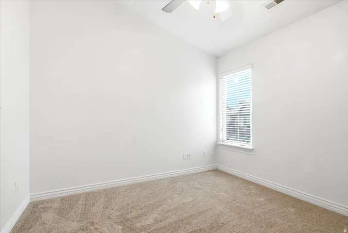 Carpeted room featuring a ceiling fan, a window with horizontal blinds, and white baseboards