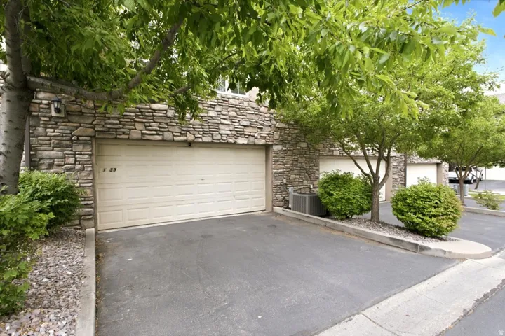 Stone veneer exterior featuring a single-car garage and mature trees