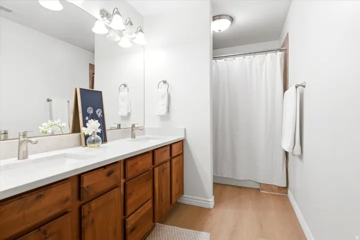 Double vanity featuring a light-colored countertop, dual undermount sinks, brushed nickel faucets, and wood cabinetry